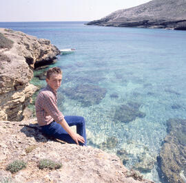 Jove assegut al costat de la mar